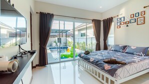 A bedroom with a bed, a TV, a desk, and a view of a swimming pool. - Green View Pool Cha-am15 (Prachuap Khiri Khan)