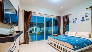 A bedroom with a bed, a TV mounted on the wall, and a view of a swimming pool through a glass door. - Green View Pool Cha-am15 (Prachuap Khiri Khan)