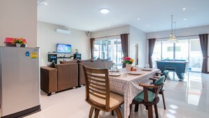 A modern living room with a dining area, a pool table, and a television. - Green View Pool Cha-am15 (Prachuap Khiri Khan)