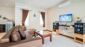 A modern living room with a sofa, coffee table, TV, speakers, and curtains. - Green View Pool Cha-am15 (Prachuap Khiri Khan)