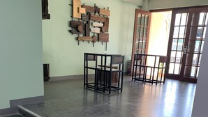 Un amplio vestíbulo con piso de mármol, una escalera y una obra de arte de madera en la pared.