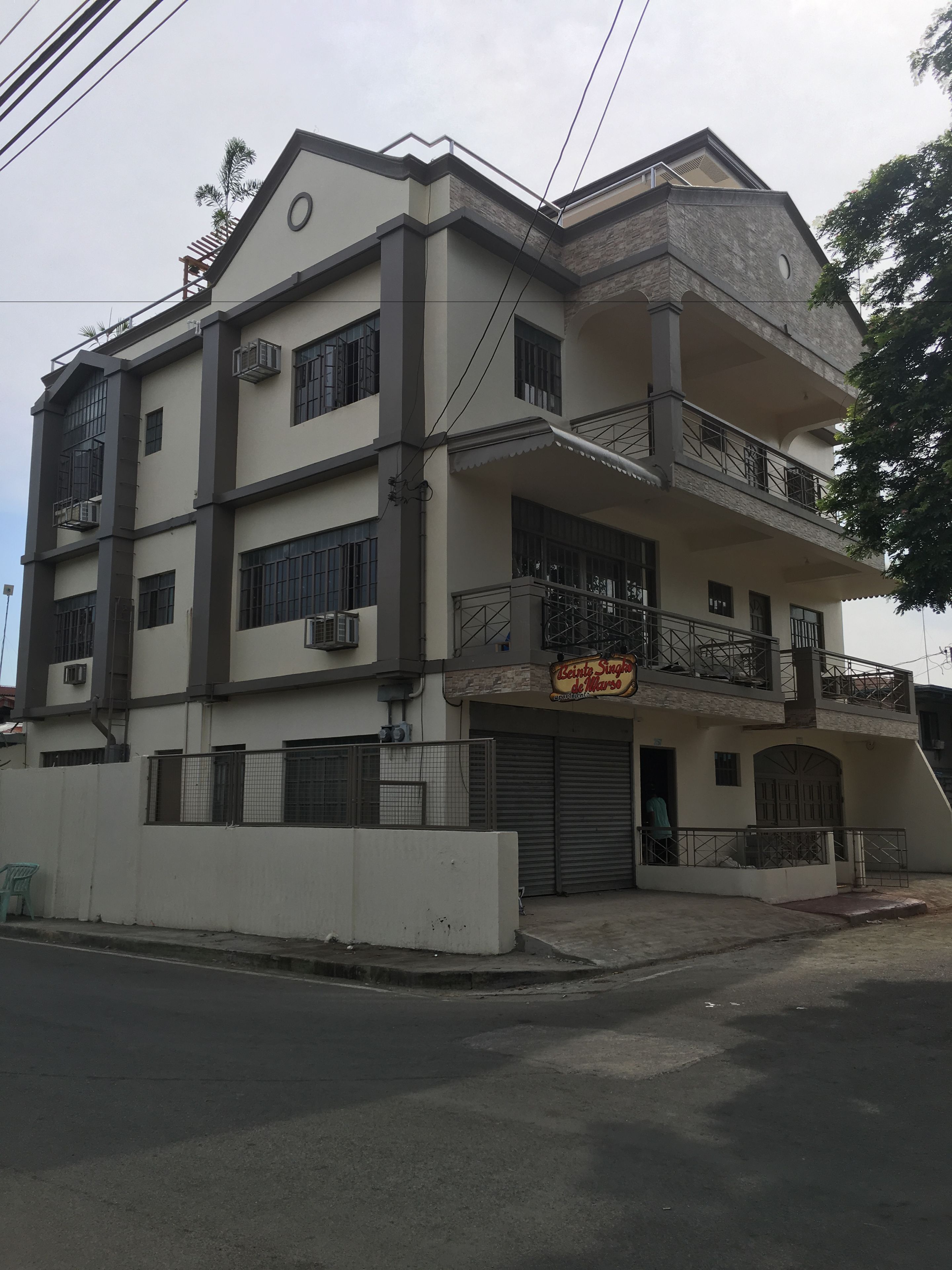 A multi-story building with balconies, air conditioning units, and a storefront.