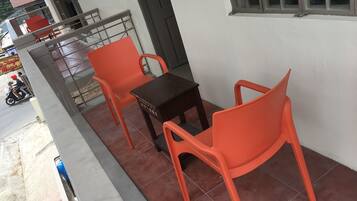 Un balcon avec deux chaises en plastique orange et une petite table en bois.