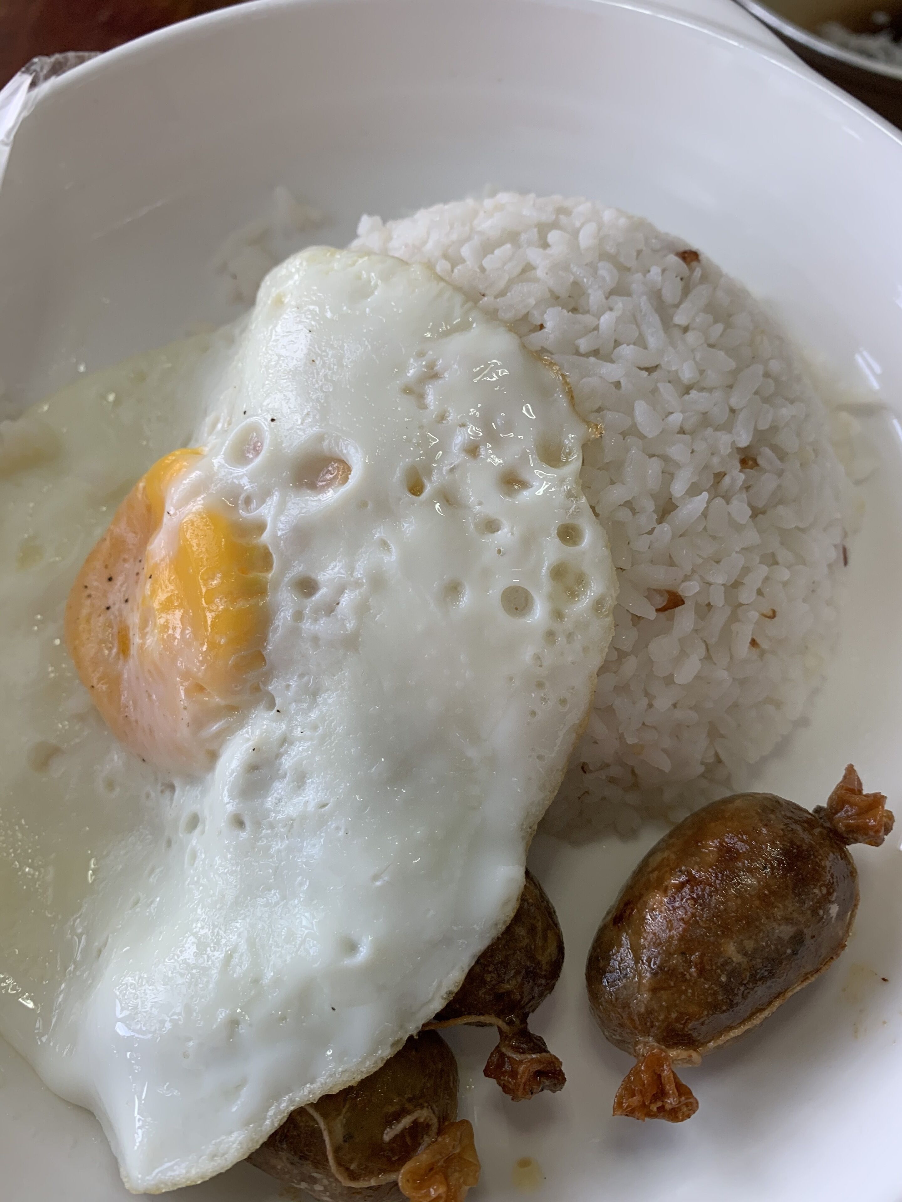 Un plato de arroz blanco con un huevo frito y dos trozos de carne.