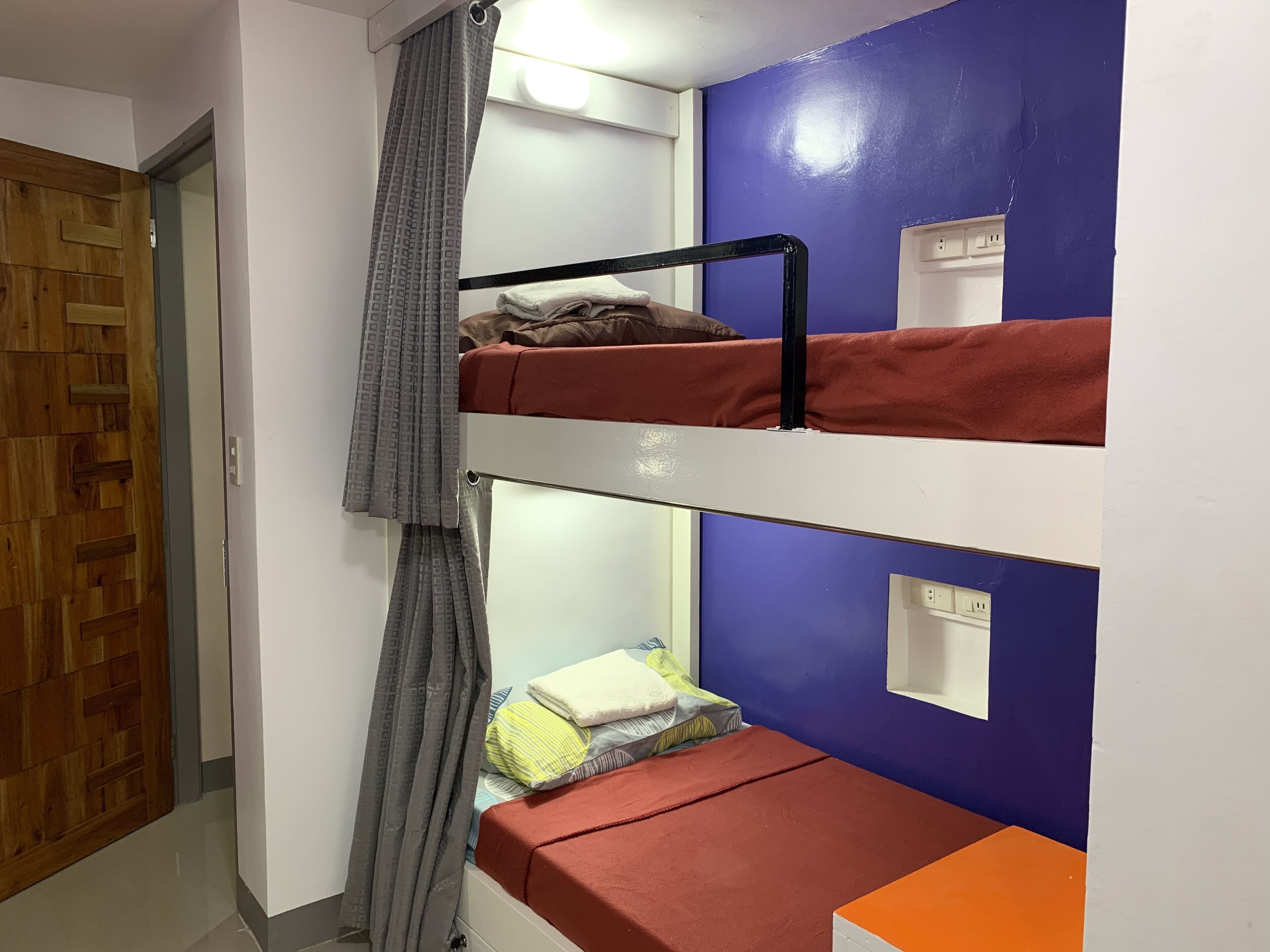 Un dormitorio con literas, una cortina y un enchufe.