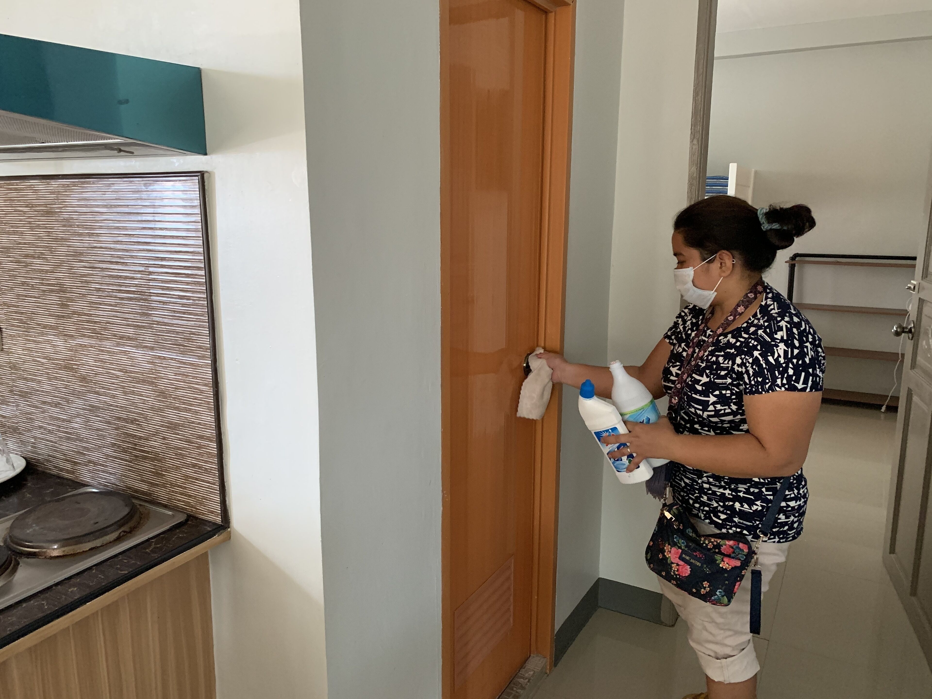 A person cleaning a door with a cloth and cleaning products.