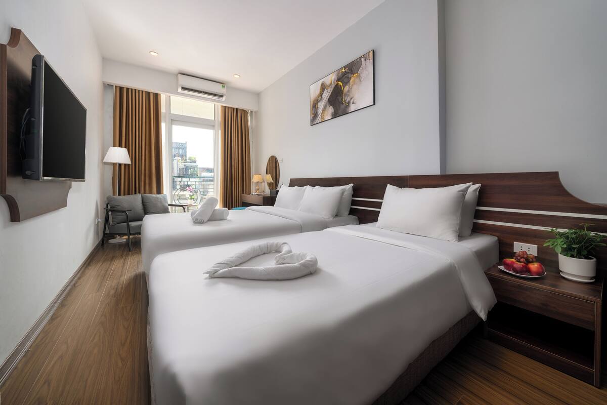 Une chambre d’hôtel avec deux lits, une télévision, un bureau avec une plante et une vue sur la ville.