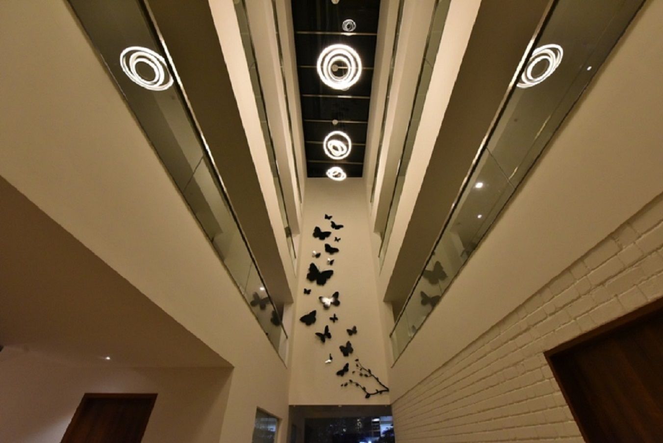 A modern interior with a high ceiling, circular light fixtures, and butterfly wall art.