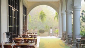 A restaurant with tables and chairs, a green carpet, and columns. - Via Appia Tagaytay (Tagaytay)
