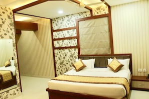 A hotel room with a large bed, a wooden headboard, and a window with blinds.