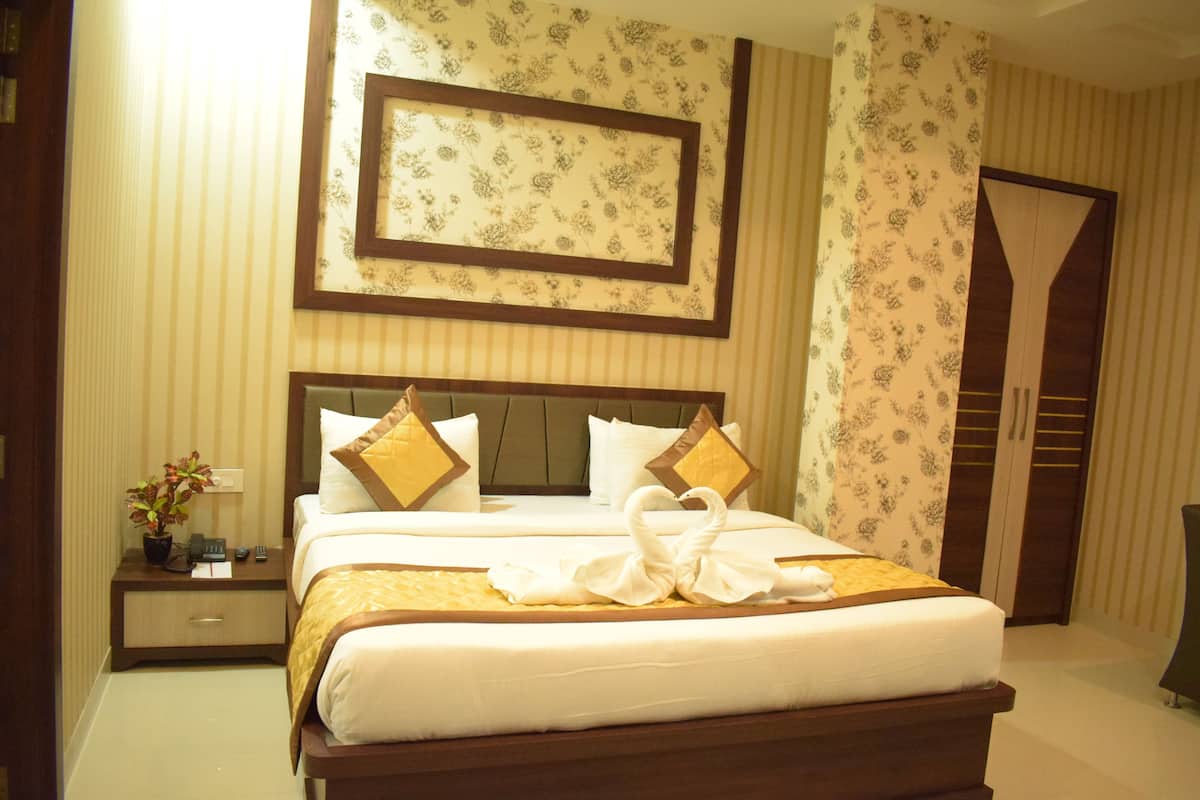 A neatly made bed with a decorative pillow arrangement, a bedside table with a plant, and a framed picture above the bed.