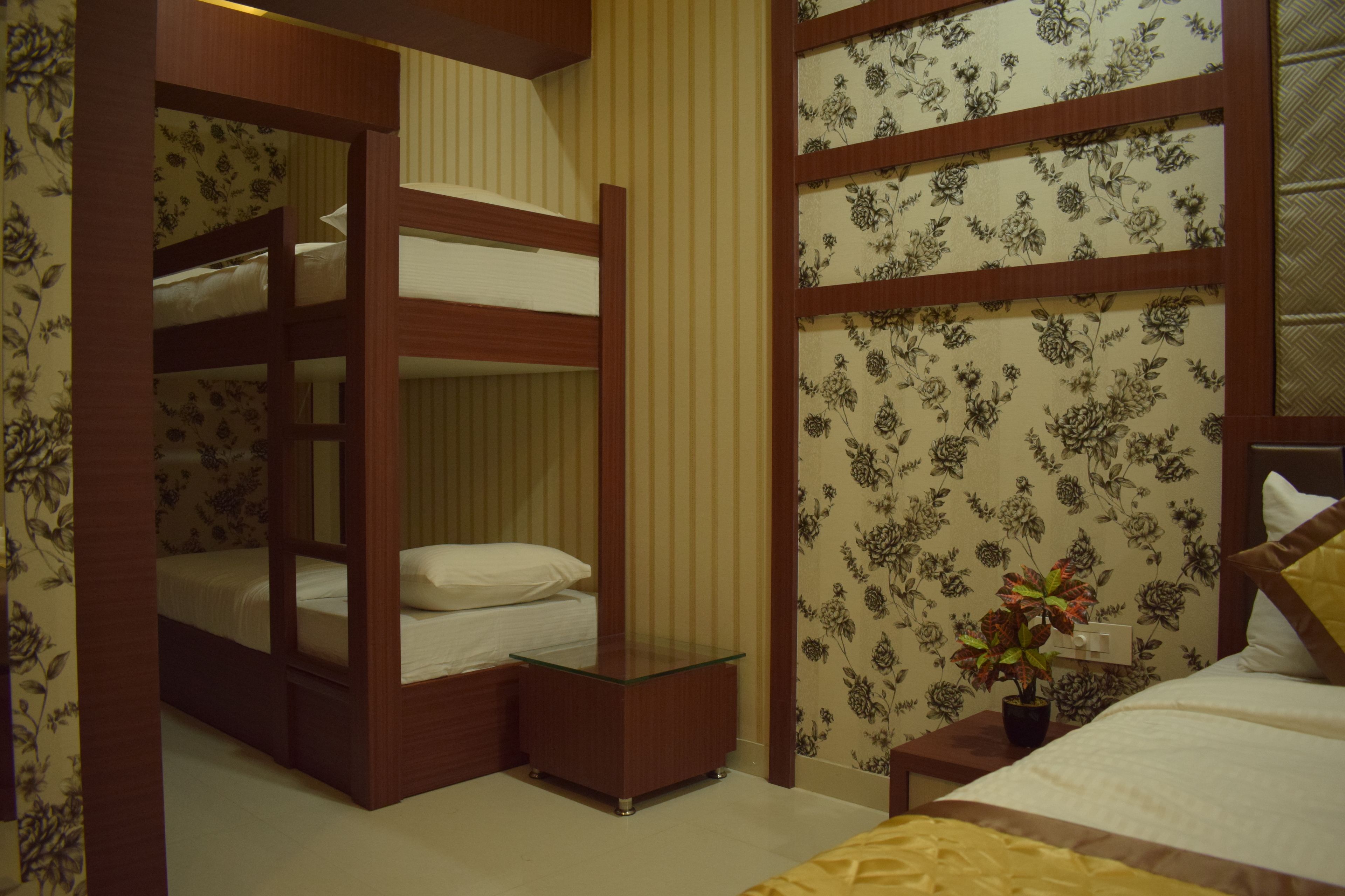 A bedroom with bunk beds, a bedside table, a nightstand, and a potted plant.