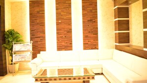 Un vestíbulo moderno con un sofá blanco, una mesa de centro de vidrio y una pared decorativa de madera.