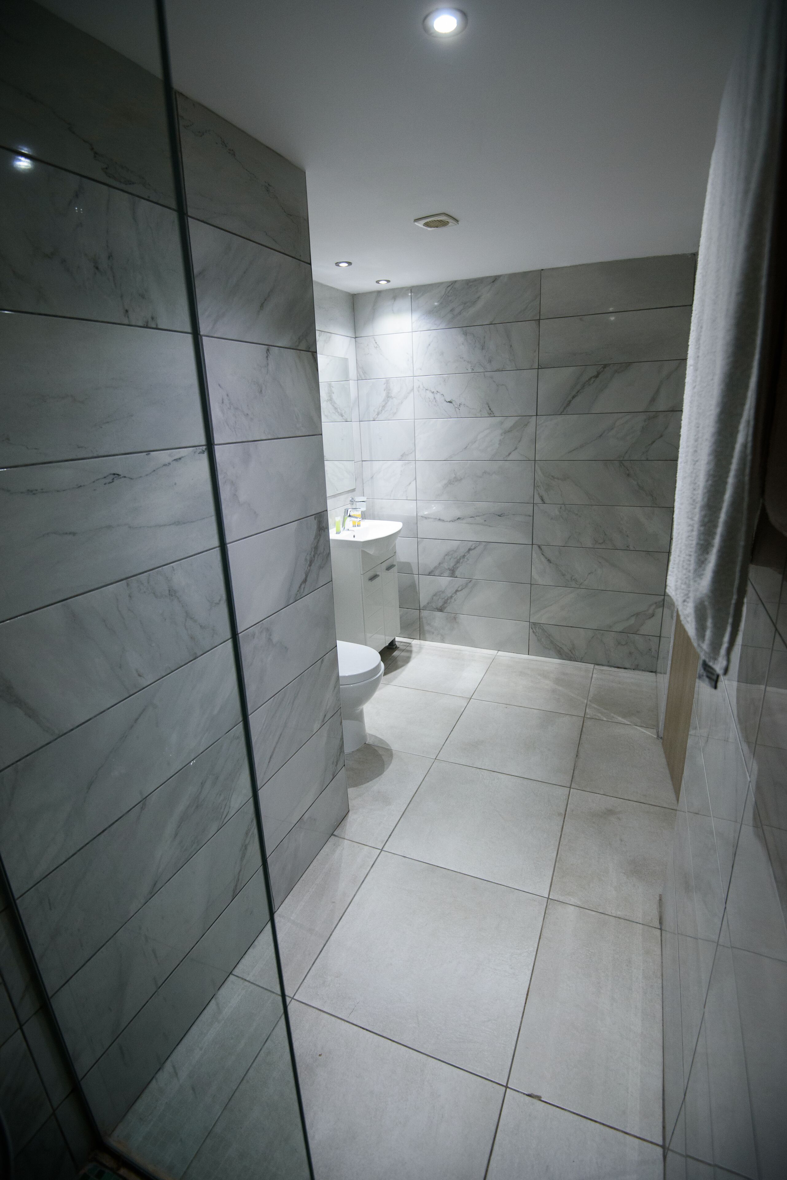A bathroom with marble walls and a white toilet.
