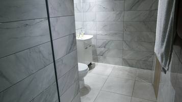 A bathroom with marble walls and a white toilet.