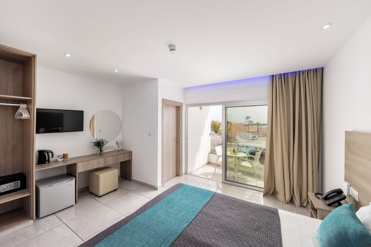Une chambre d’hôtel moderne équipée d’un lit, d’un bureau et d’une télévision.