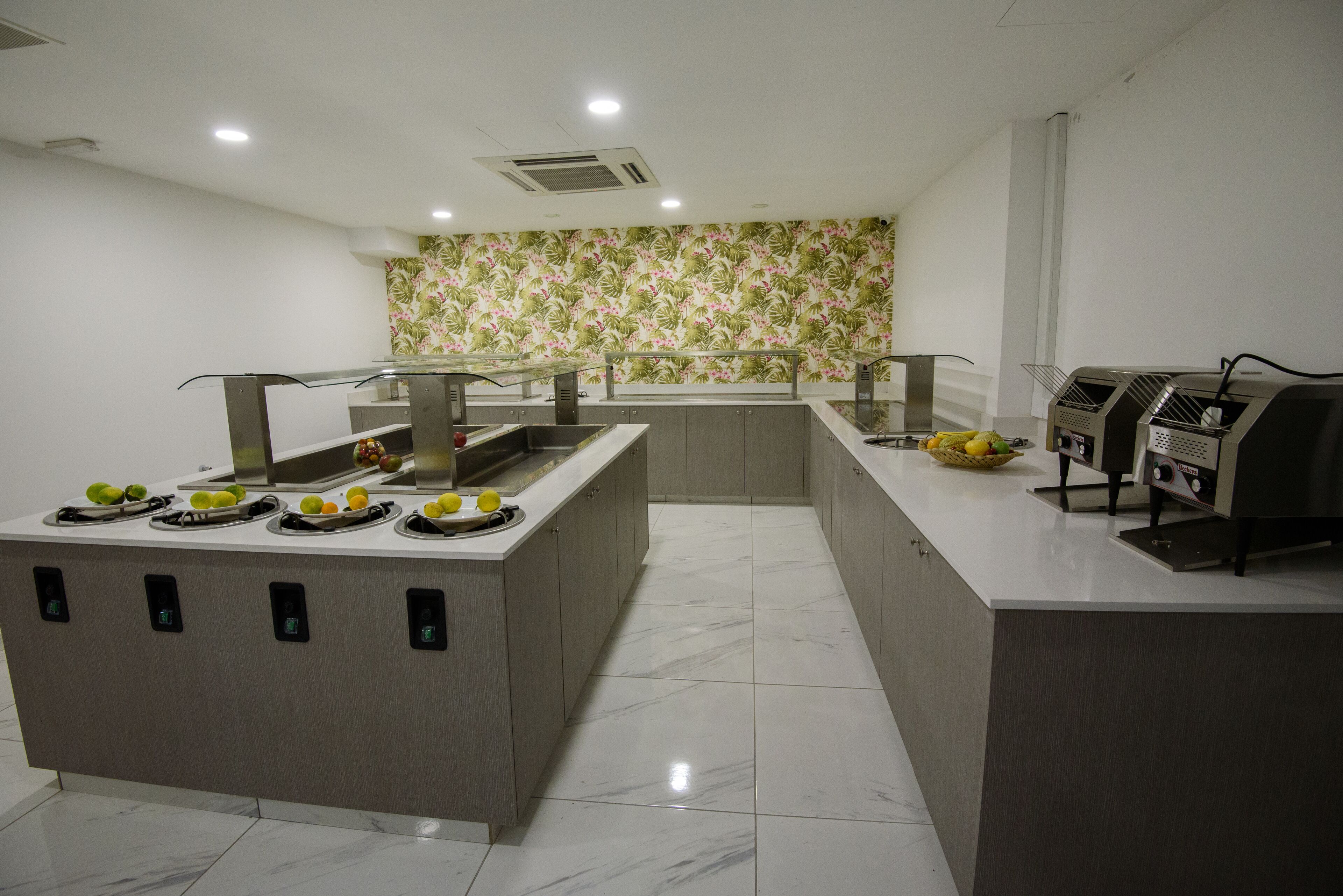 A modern kitchen with a marble countertop, a fruit display, and a built-in grill.