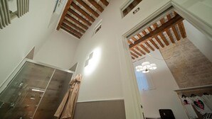 Une salle de bain moderne avec une douche en verre, des poutres en bois au plafond et un mur d’accent en pierre.