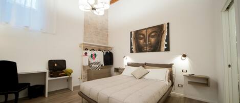 Un dormitorio con cama, mesitas de noche, una silla, armario y una obra de arte colgada en la pared.