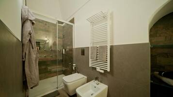 Un baño moderno con cabina de ducha de vidrio, un bidé y un perchero para toallas.