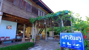 A wooden building with a covered patio area, outdoor seating, and a sign indicating WiFi availability. - Huenhimphu Resort (Phu Phan)