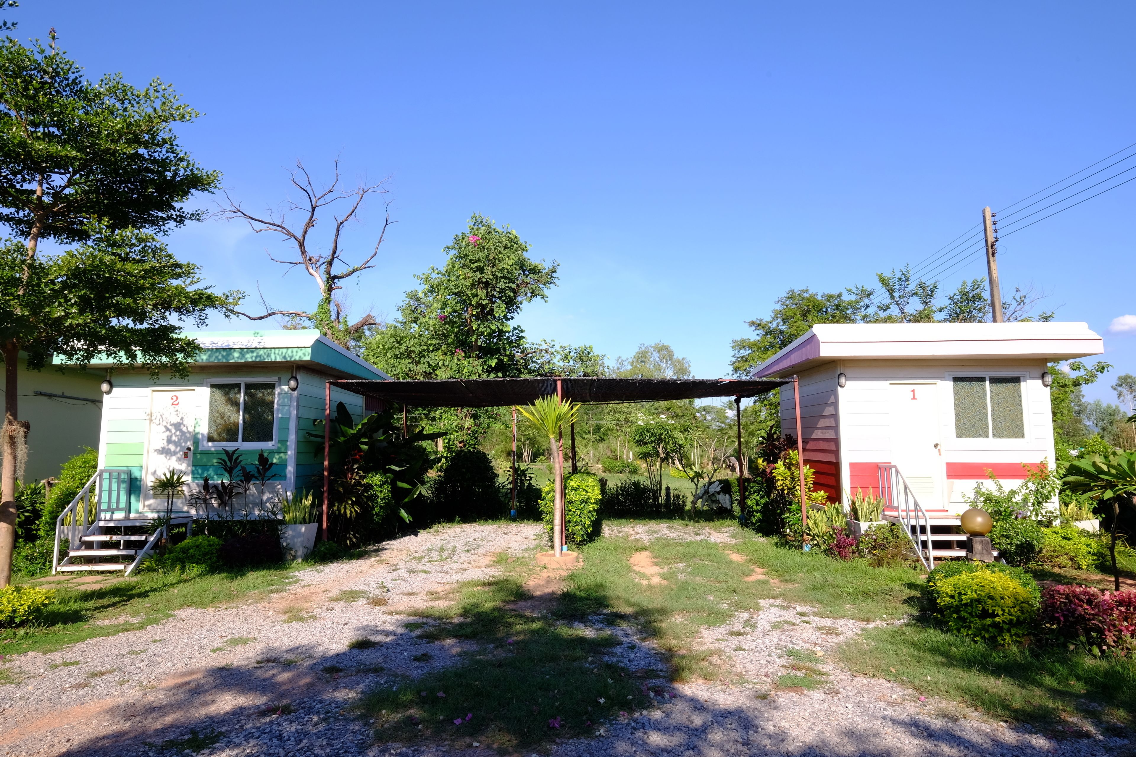 Duas casas móveis com um caminho de acesso de cascalho e vegetação ao redor.