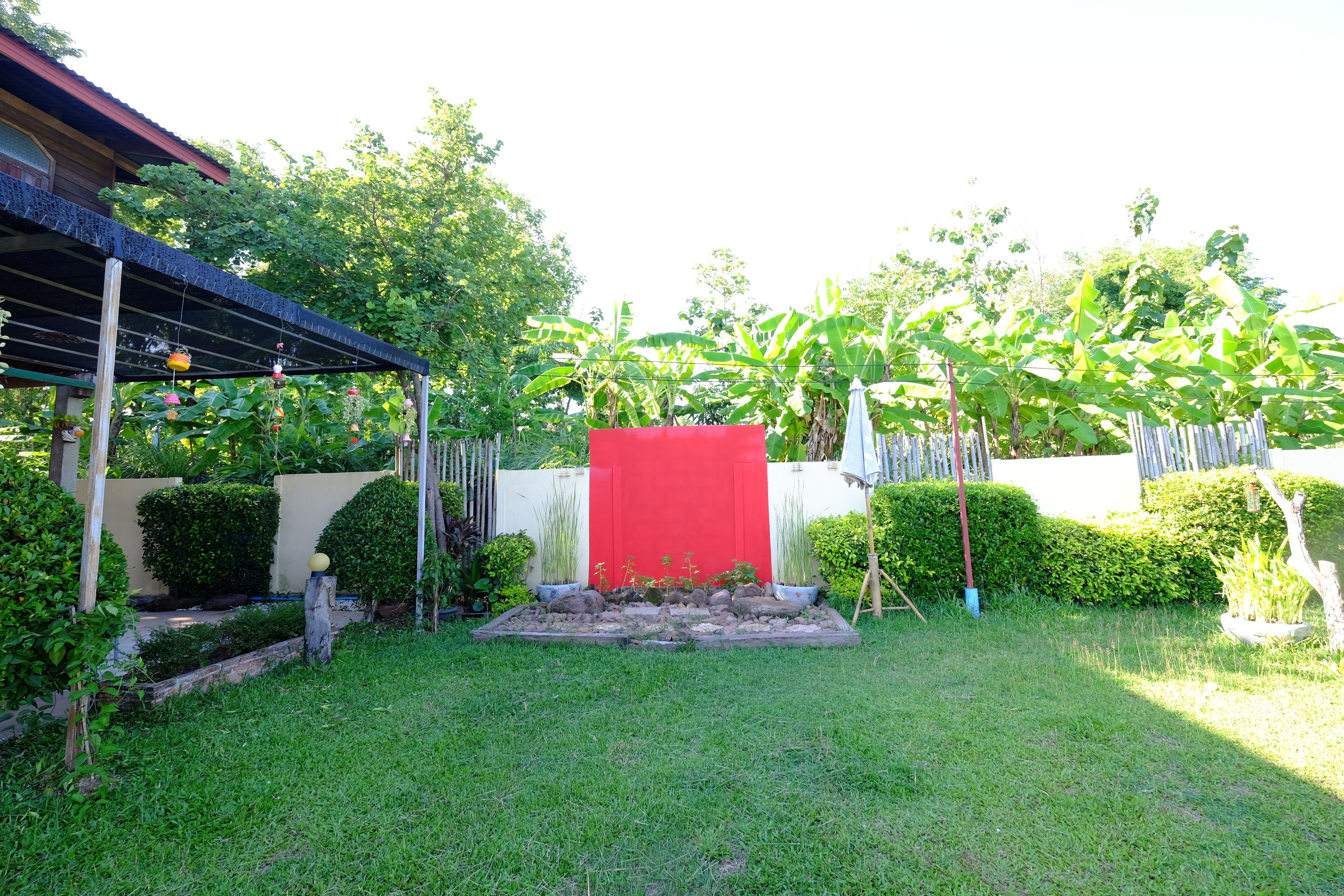 A well-maintained garden with a red structure, various plants, and a wooden pergola.