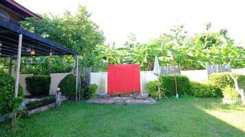 A well-maintained garden with a red structure, various plants, and a wooden pergola.