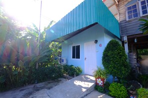 Una casa con fachada azul, una puerta blanca y un pequeño porche.