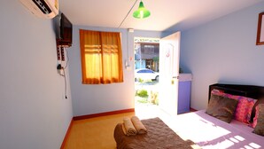 A bedroom with a bed, a TV, and a window with curtains. - Huenhimphu Resort (Phu Phan)