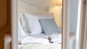 Un dormitorio con cama, almohadas, una lámpara de noche y un espejo.