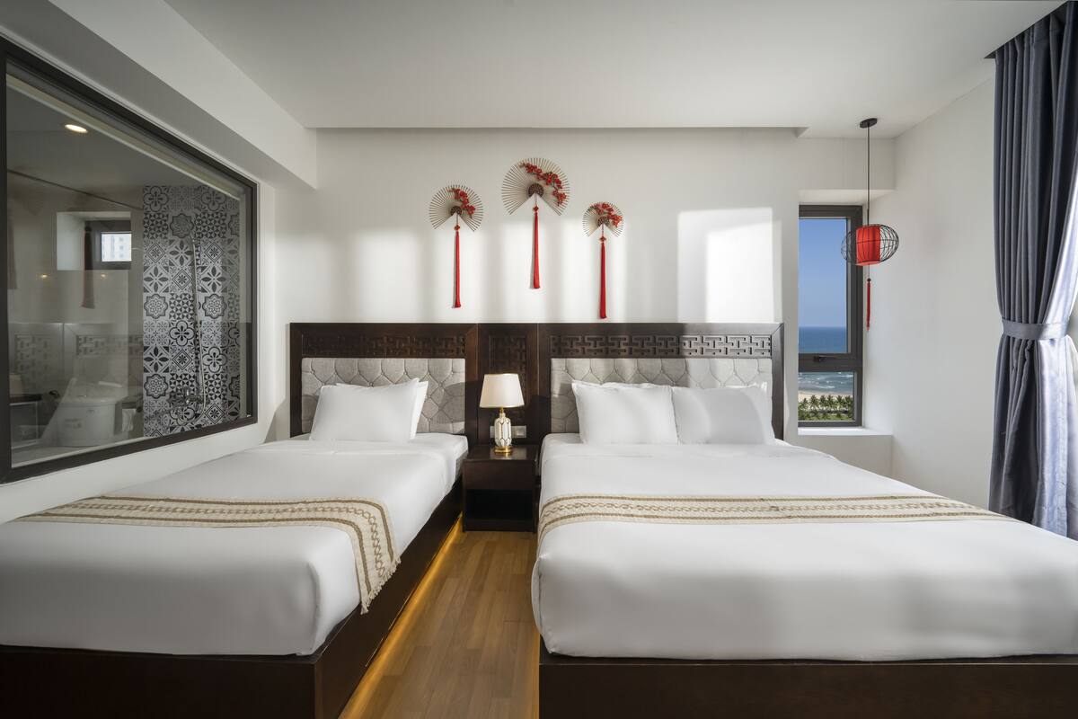 A hotel room with two beds, a large window with a view, and decorative wall art.