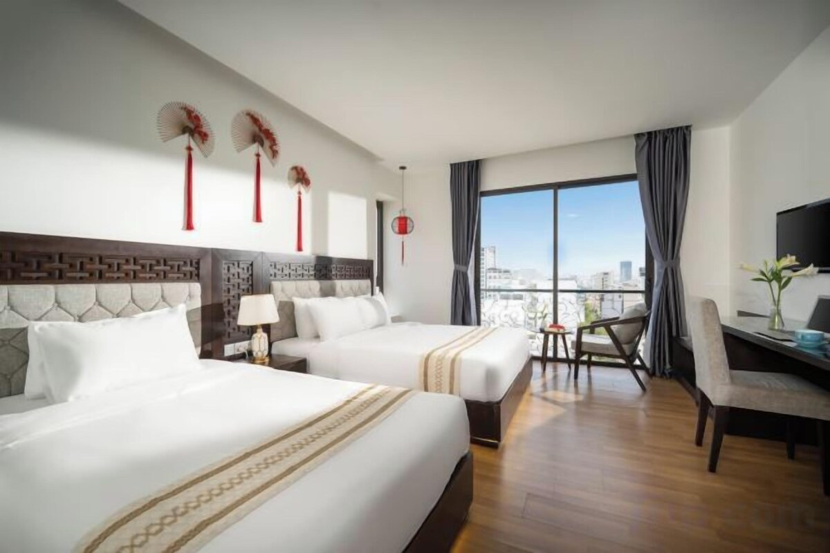 A hotel room with two beds, a desk, and a chair.