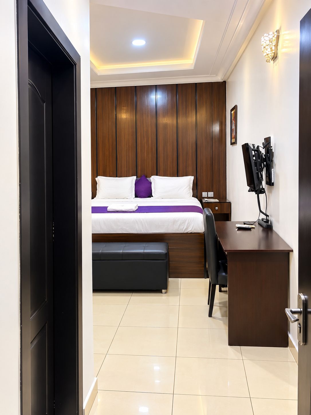 A hotel room with a bed, a desk, a chair, and a television.