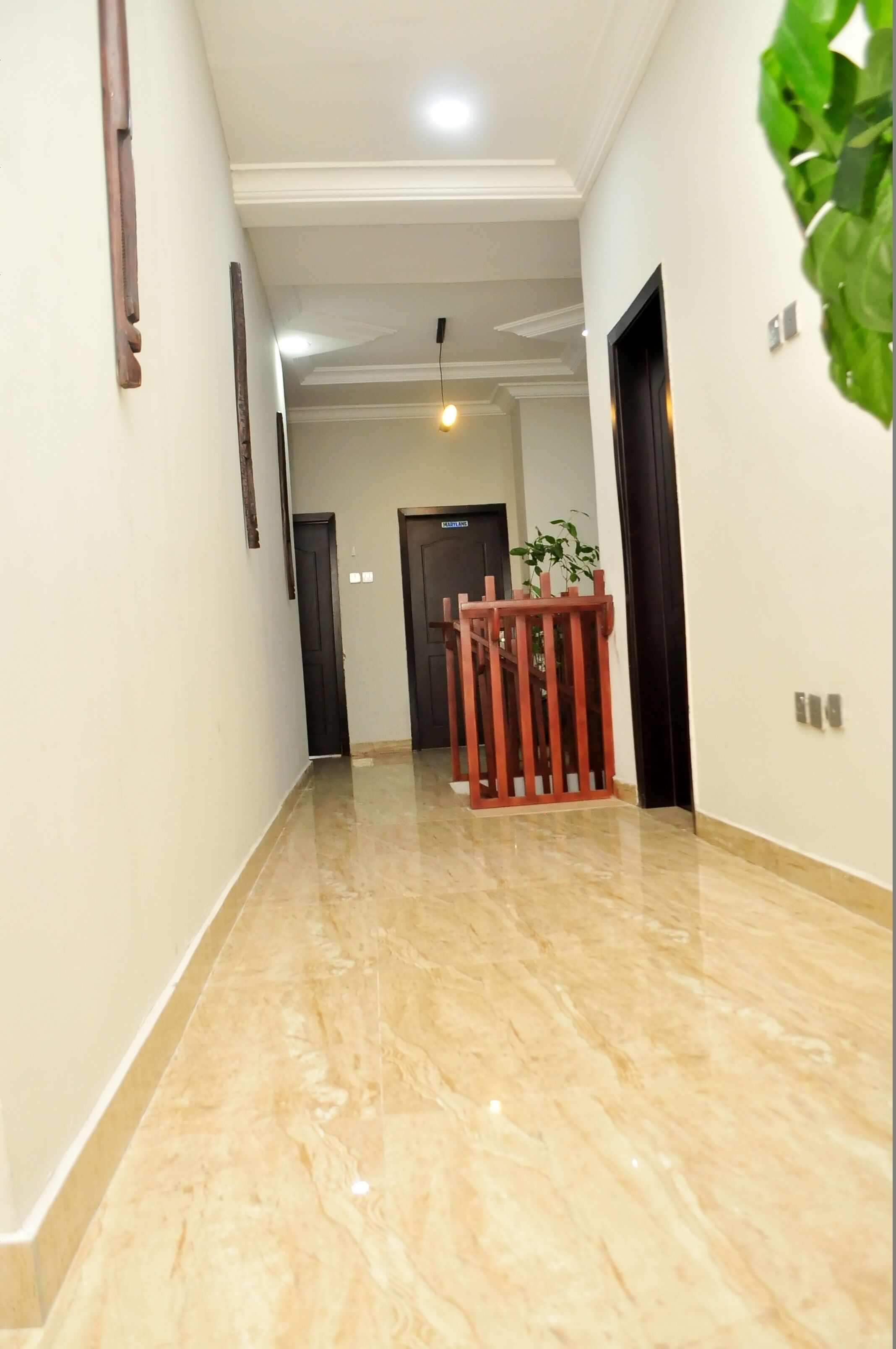 A hallway with a marble floor, wooden doors, and a small table with a plant.