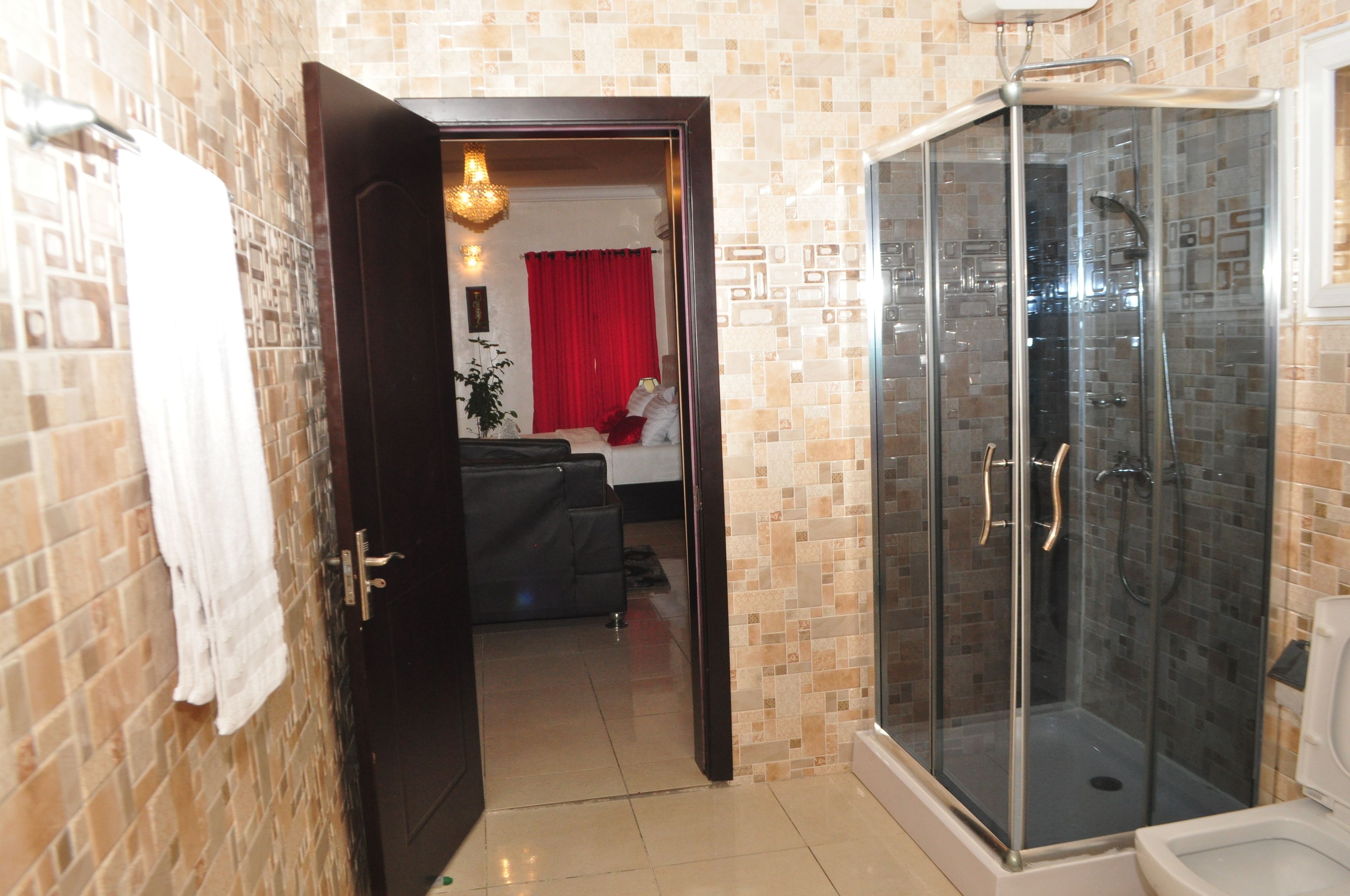 Une salle de bain avec une douche à parois de verre, des toilettes et une serviette accrochée au mur.
