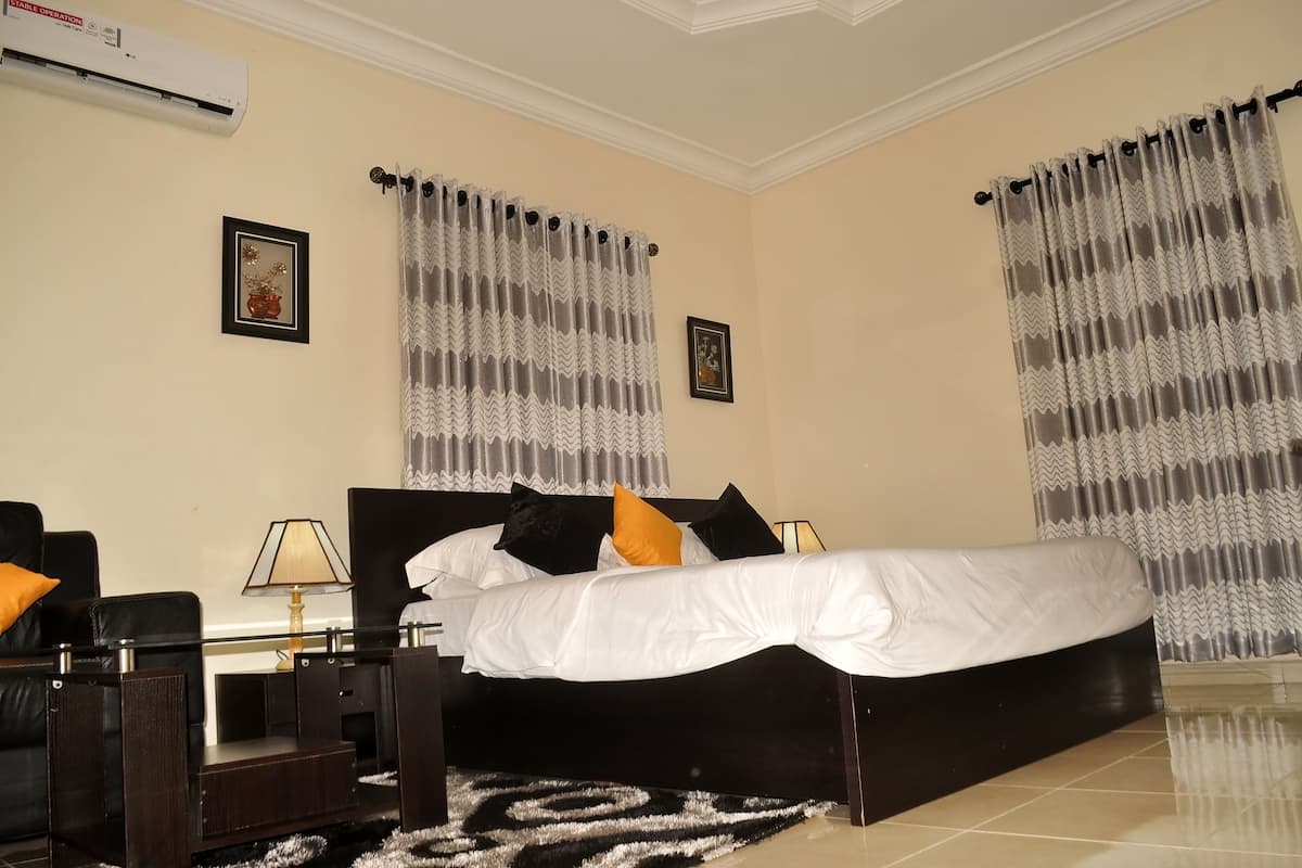 A hotel room with a large bed, two bedside tables, a lamp, and a decorative rug.