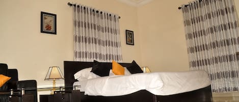 Une chambre d’hôtel avec un grand lit, deux tables de chevet, une lampe et un tapis décoratif.