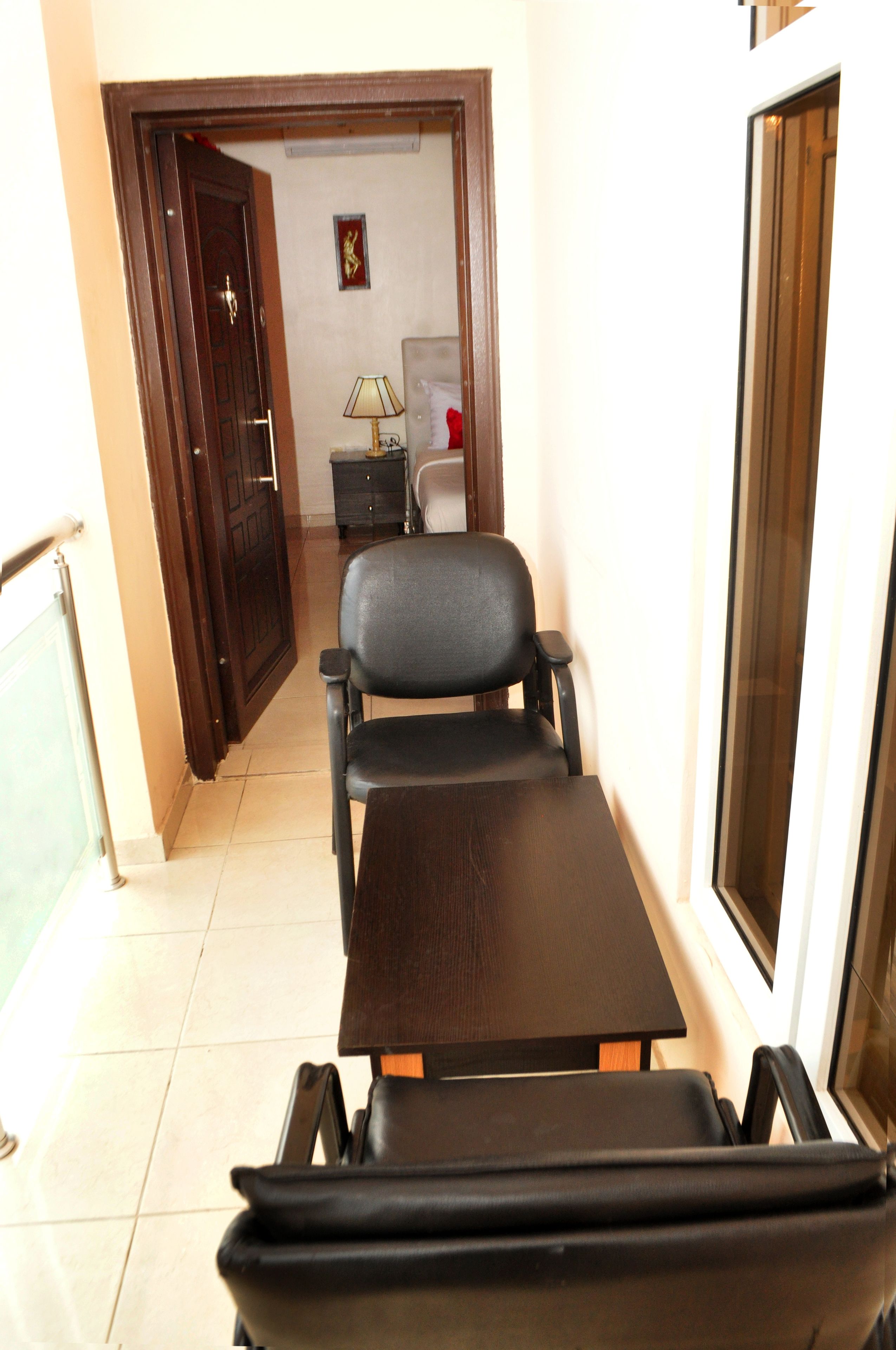A room with a bed, a desk, and a chair. There is a door leading to another room.