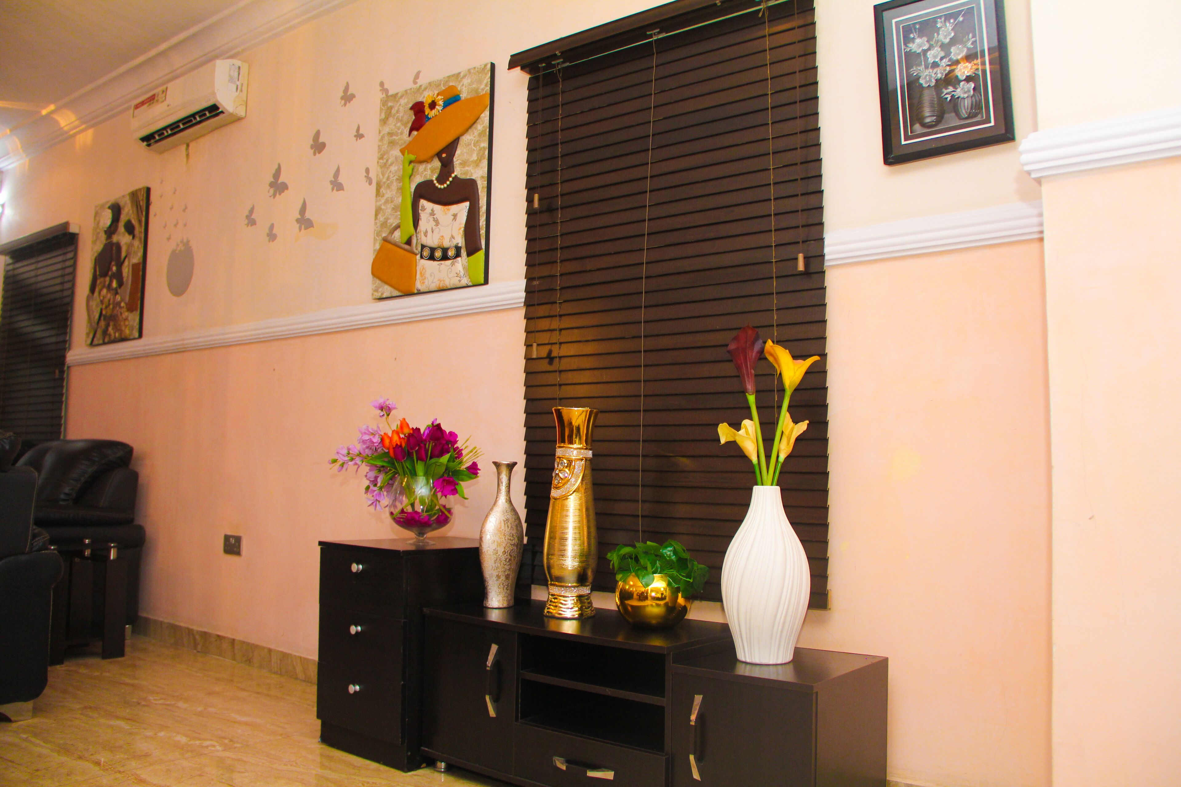 Ein Zimmer mit einer schwarzen Unterhaltungsanlage, einer weißen Vase mit gelben Blumen und einer dekorativen Vase mit einer Pflanze.