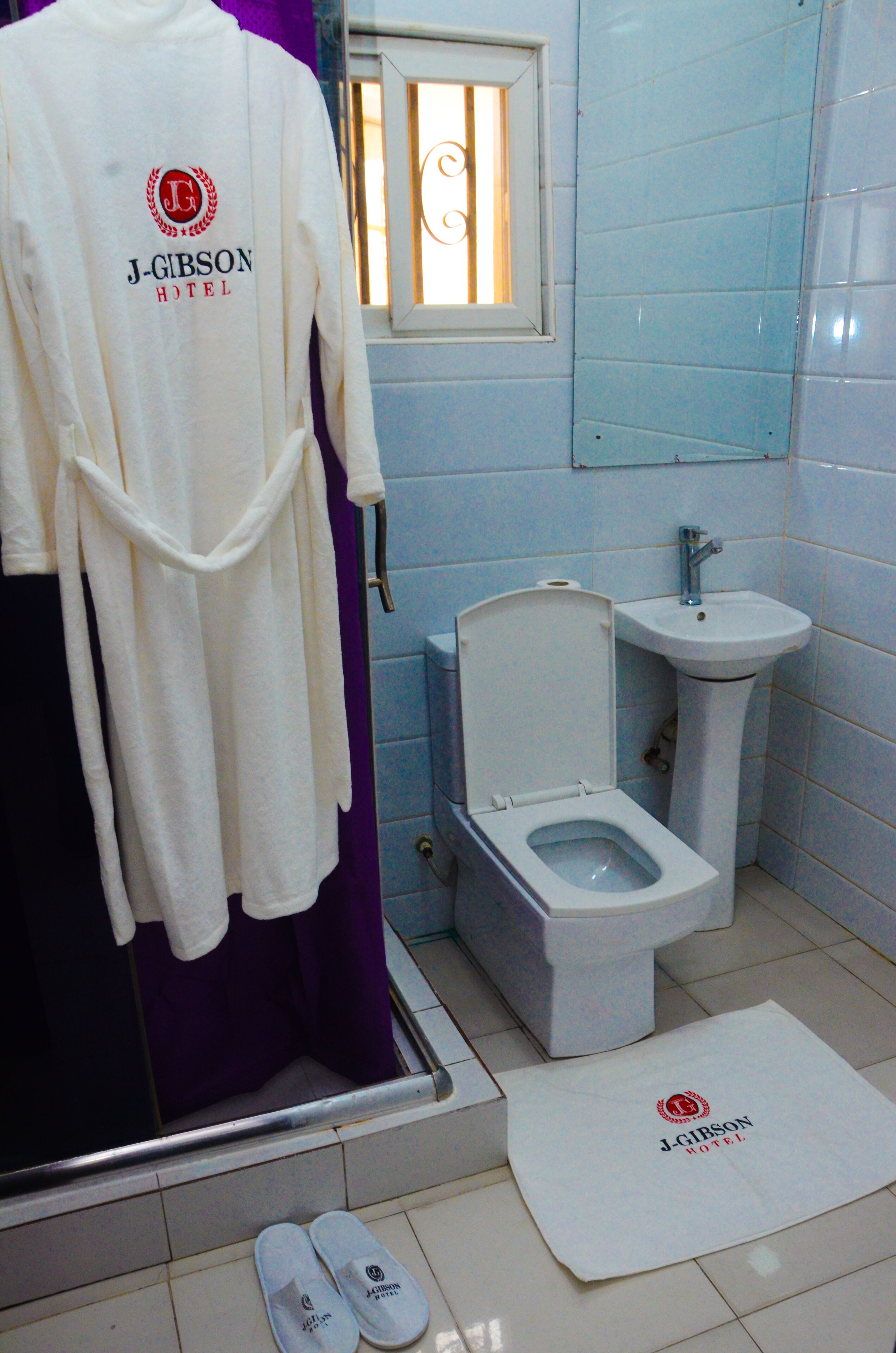 Un bagno con una vasca da bagno bianca, un water bianco, un lavandino bianco e una finestra con inferriate.