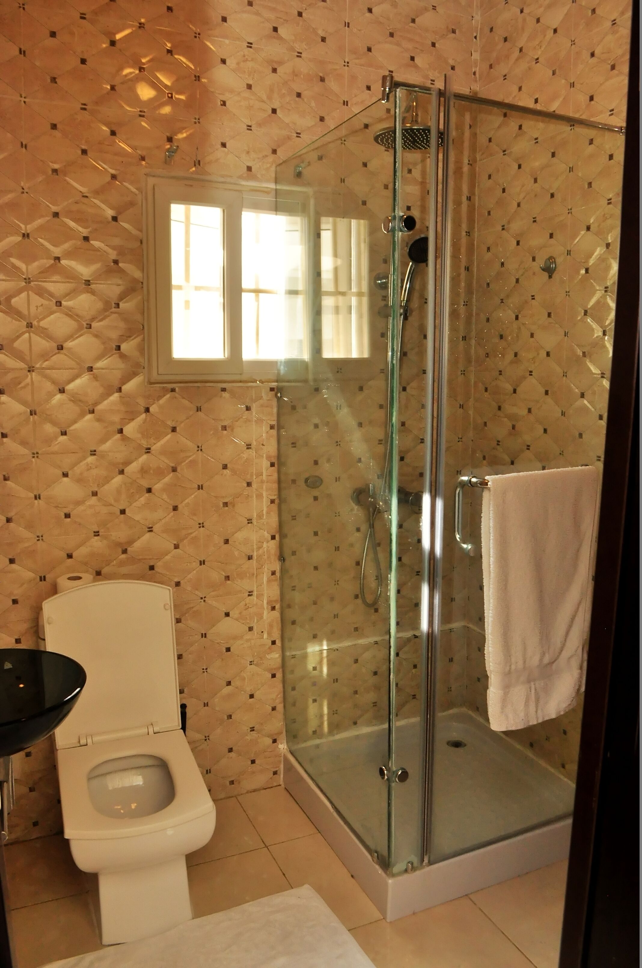 A bathroom with a glass-enclosed shower, a toilet, and a sink.