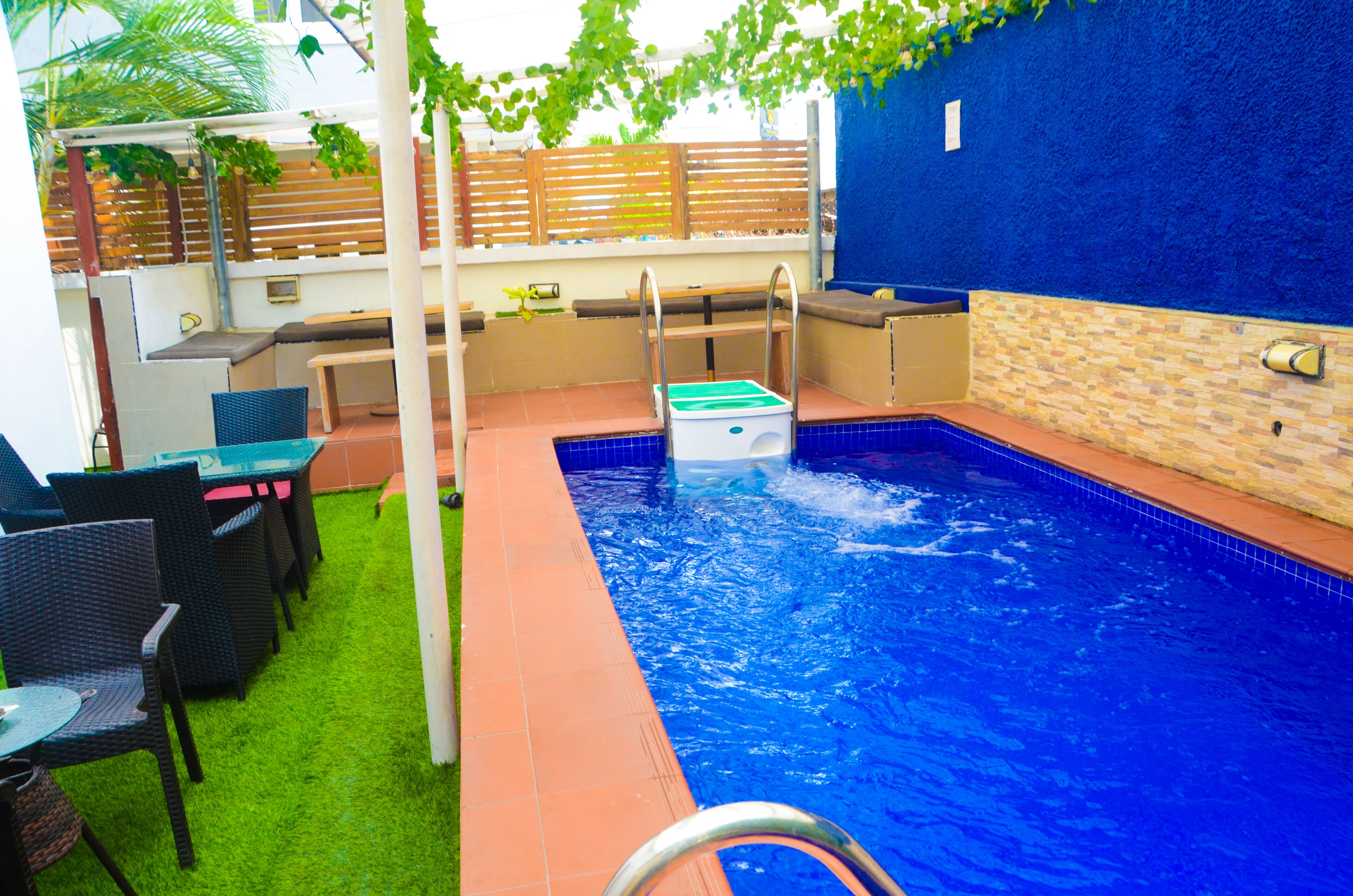 Une piscine avec une terrasse en bois, un banc et une table avec des chaises.