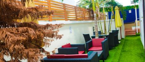 An outdoor seating area with wicker furniture and a green artificial turf.