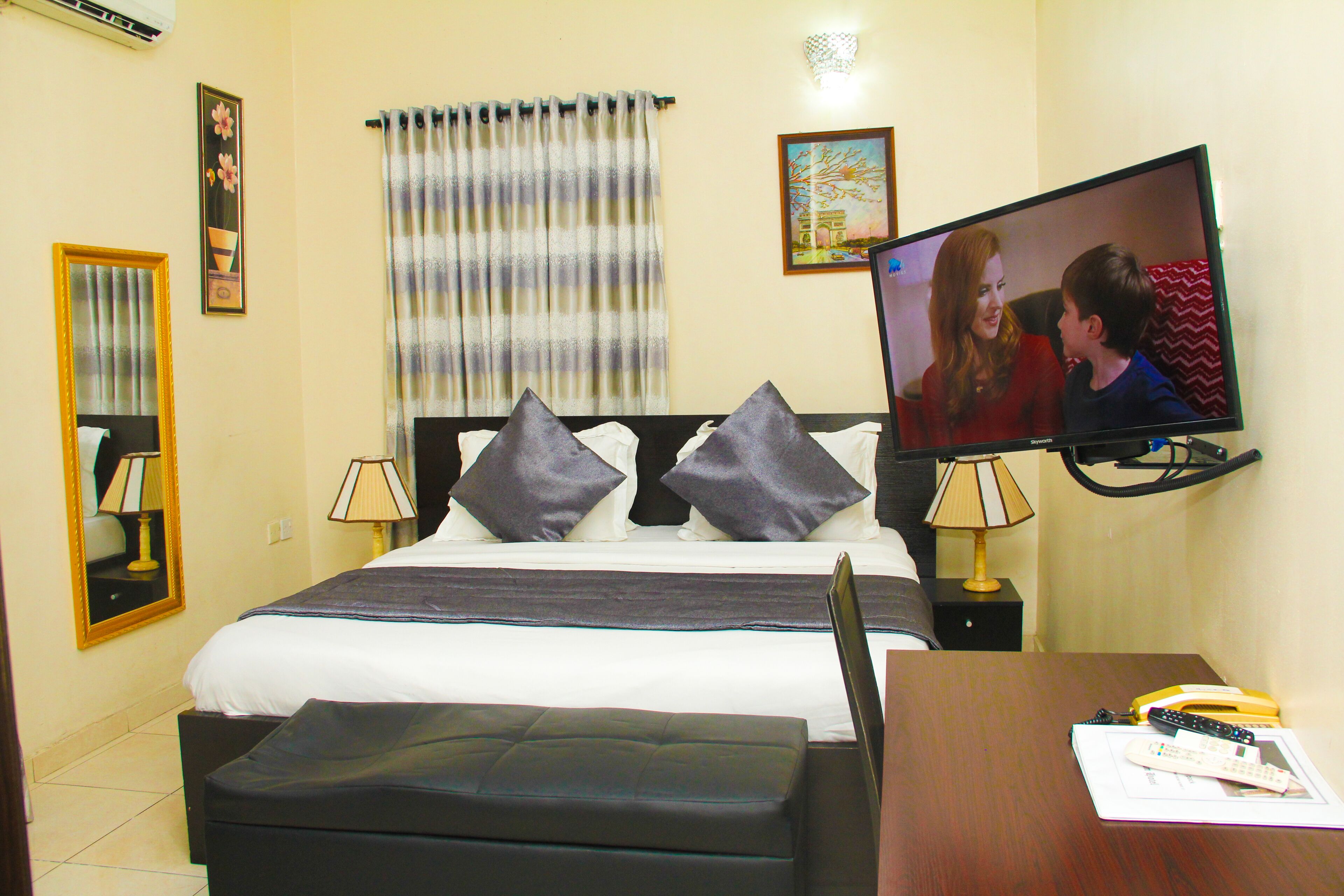 A hotel room with a bed, two bedside tables, a TV, and a desk with a chair.