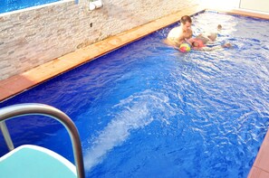 A swimming pool with a brick wall and a metal pool ladder. - J. Gibson Hotel (Lekki)