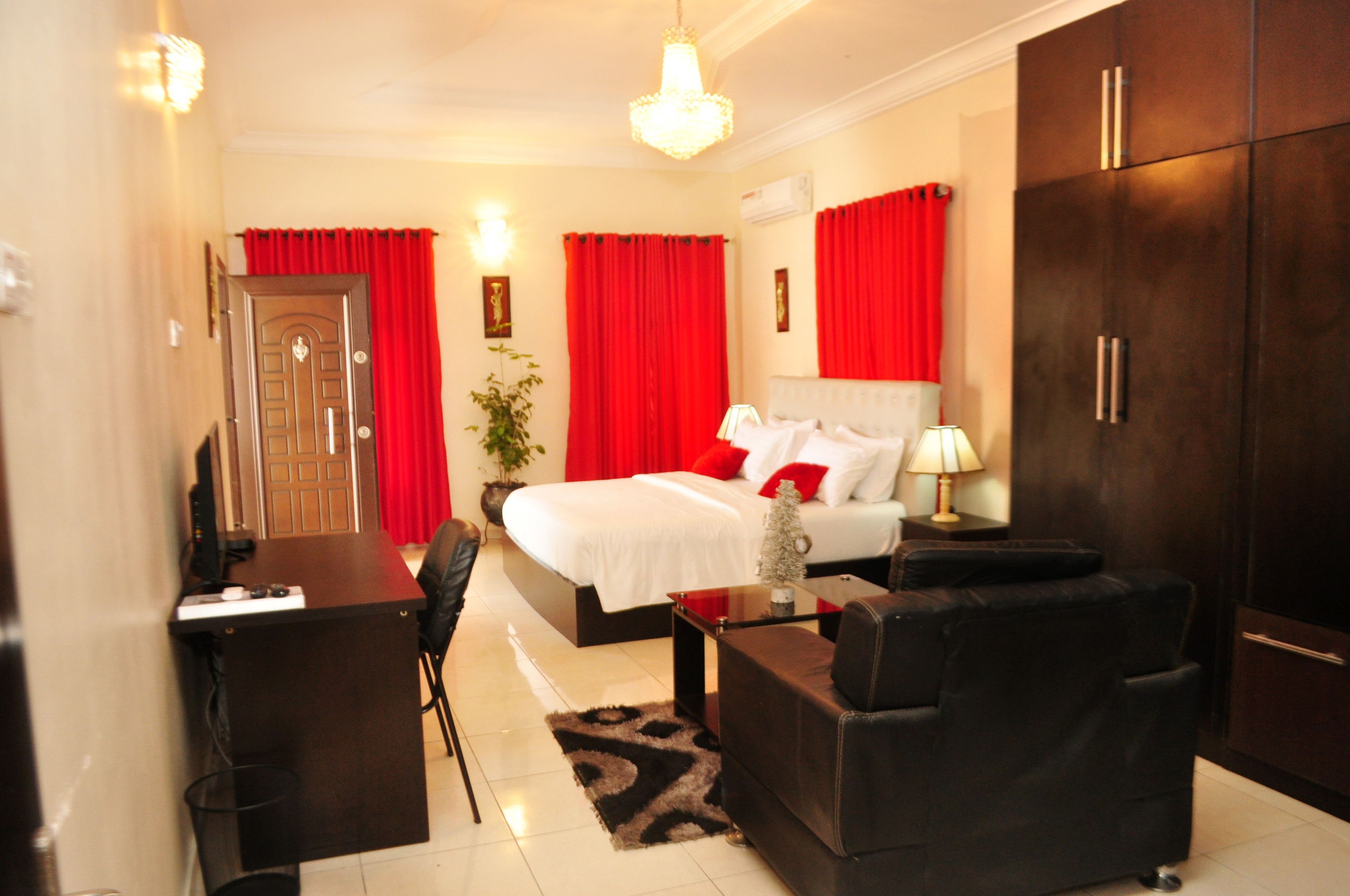 A hotel room with a bed, a desk, a chair, a sofa, and a wardrobe.