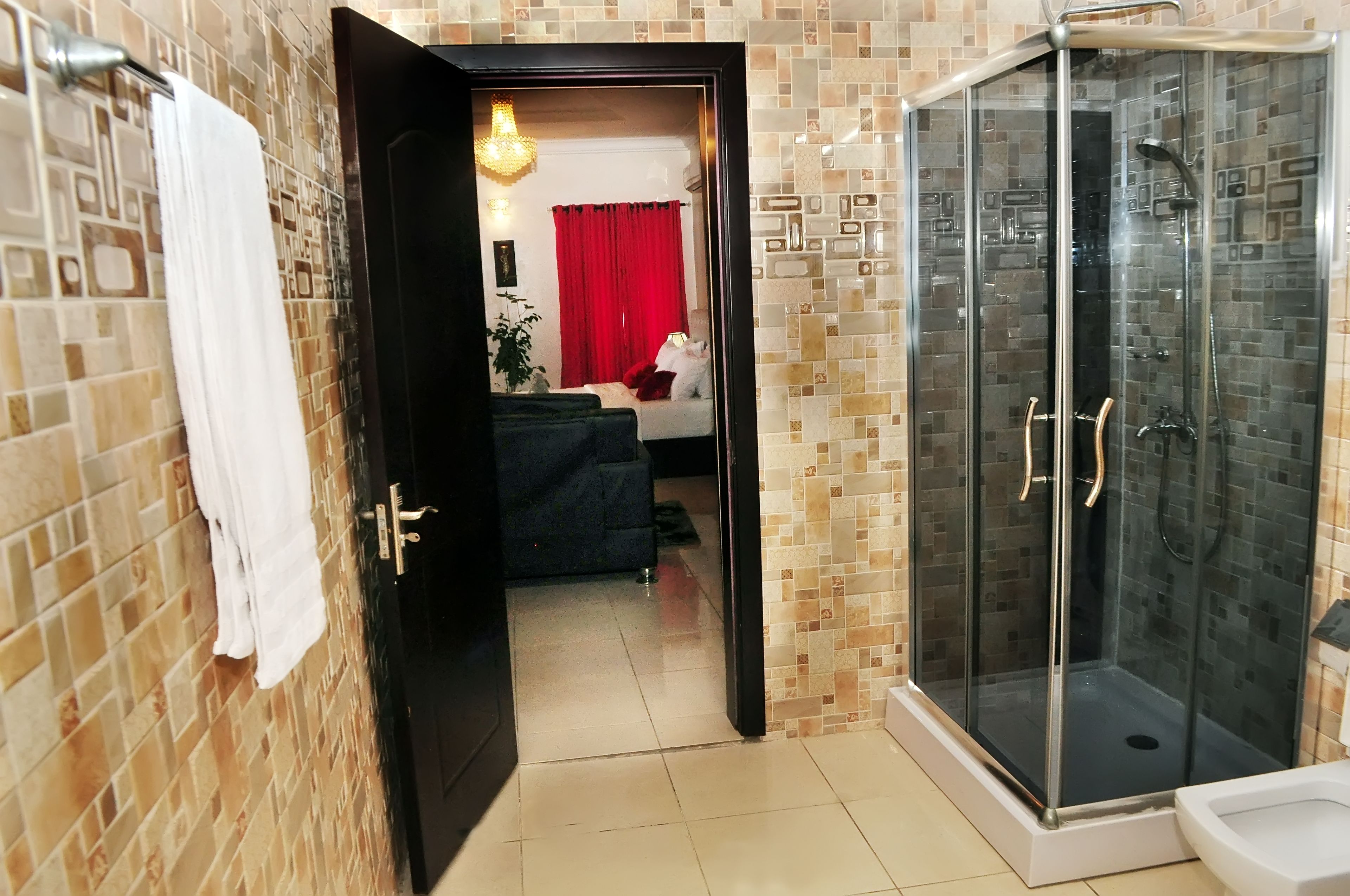 A bathroom with a glass-enclosed shower, a white toilet, and a towel hanging on a rack.