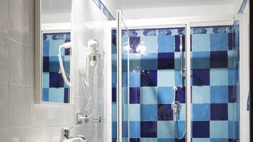 Um banheiro com piso xadrez, pia branca, vaso sanitário e chuveiro com azulejos azuis.