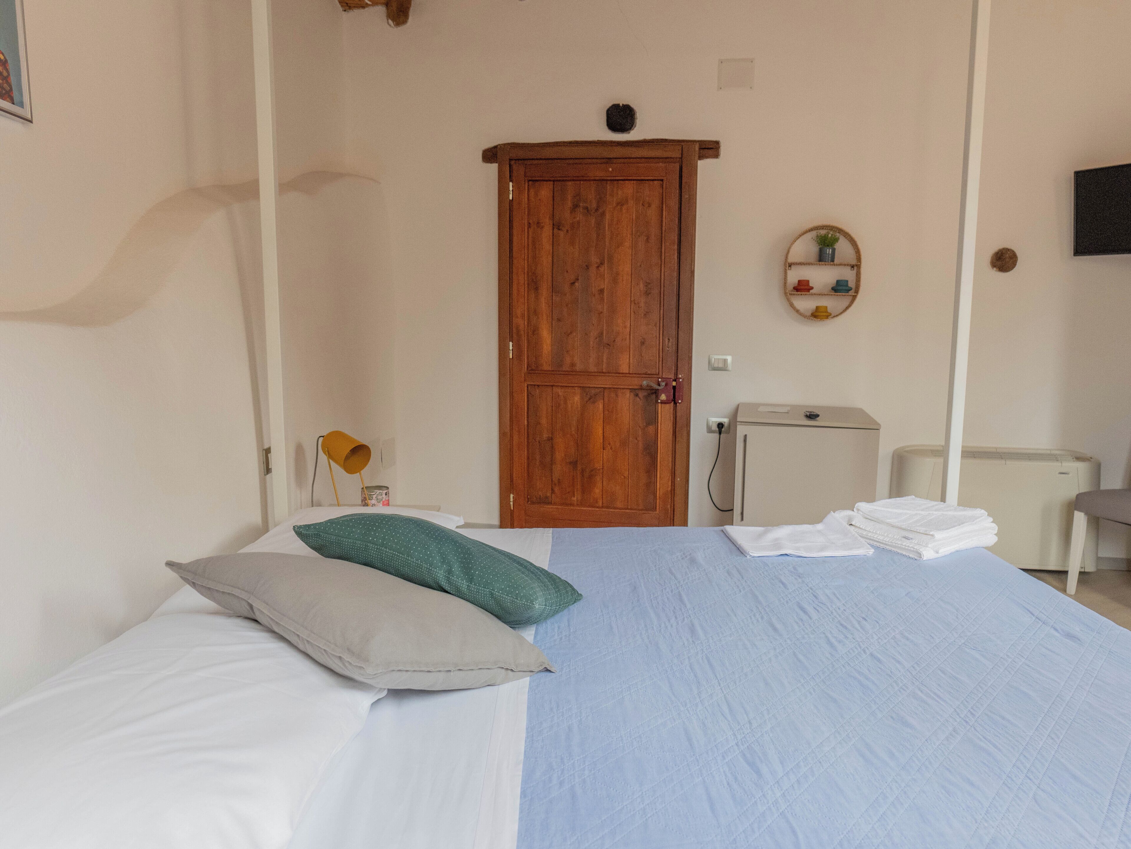 Ein Schlafzimmer mit einem Bett, einem Holzschrank, einem kleinen Schreibtisch und einer Heizung.